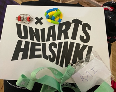 Fidget toys placed on top of a paper file that reads ‘UNIARTS HELSINKI’, with a name tag with a lime green strap and name ‘KAI’.
