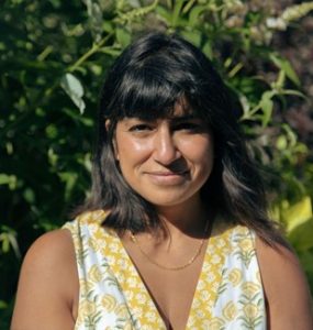 A photo of a woman with black hair wearing a yellow and white top