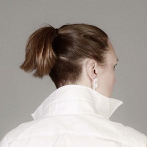 A photo of a woman with a pony tail, wearing a white shirt, taken from behind