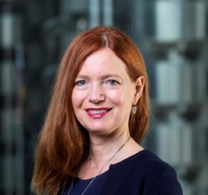 A photo of a woman with red hair who is wearing a black top.